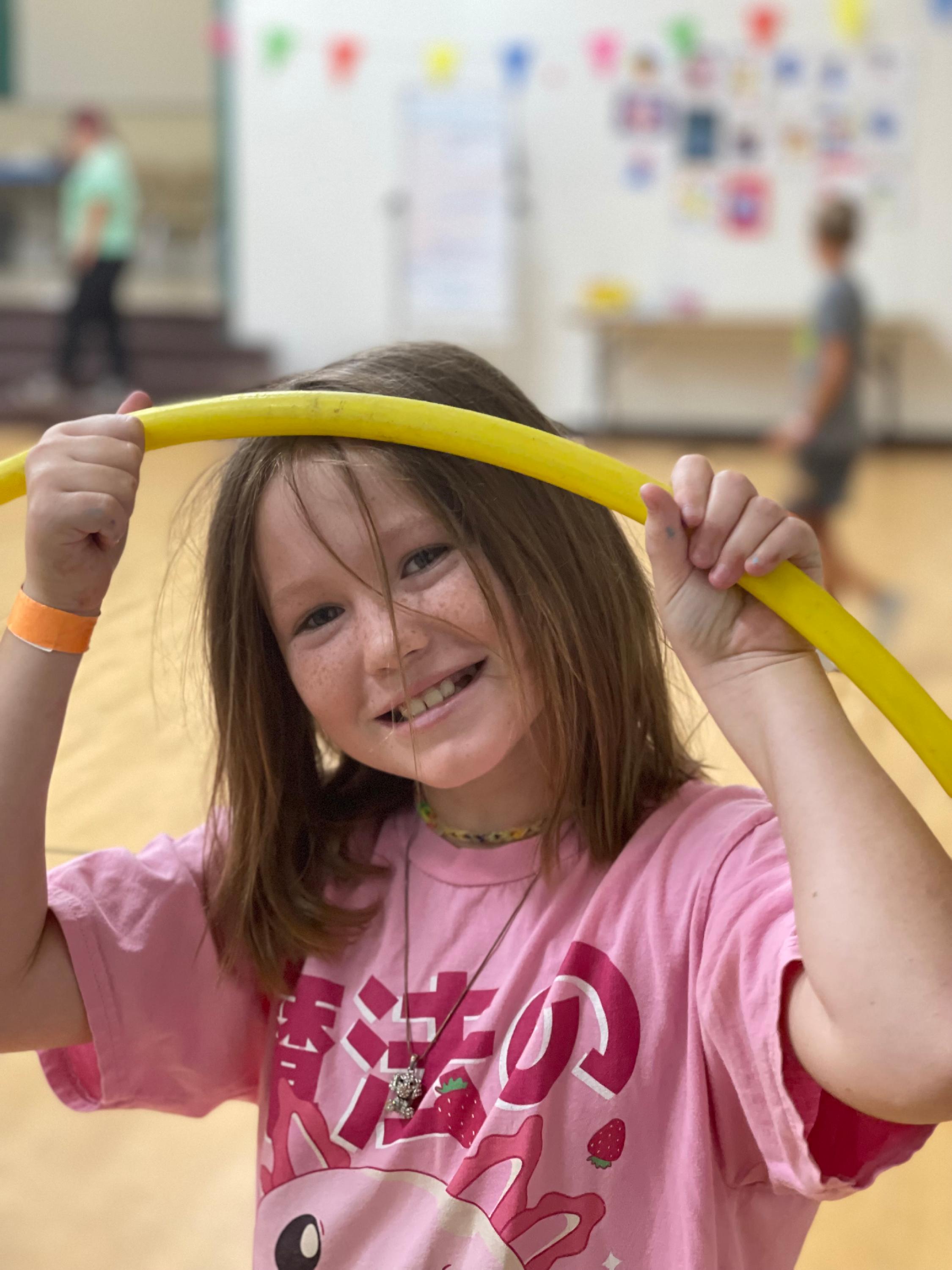 A cheerful young girl holds a hula hoop